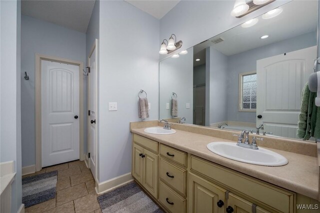 full bath featuring baseboards, visible vents, a sink, and double vanity