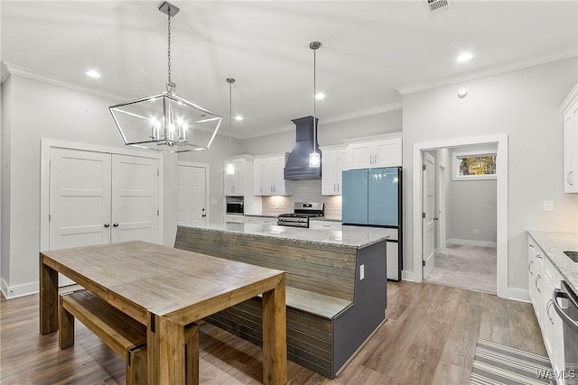 11480 Saint Joseph St, Northport, AL 35475 - kitchen with stainless steel gas stove, premium range hood, white cabinetry, backsplash, and fridge