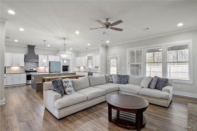 living room featuring crown molding, wood-type flooring, and ceiling fan with notable chandelier