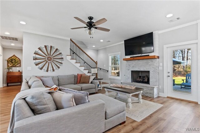 living room featuring stairway, visible vents, wood finished floors, and ornamental molding