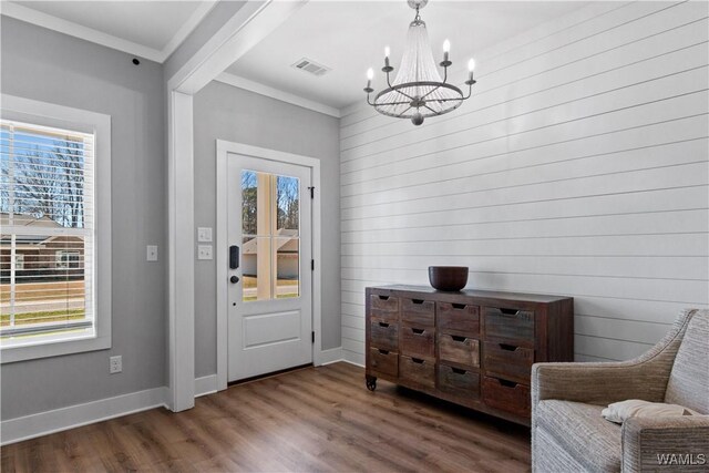 interior space with crown molding, wood finished floors, visible vents, and a healthy amount of sunlight