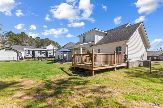 back of property featuring a lawn, a deck, and fence