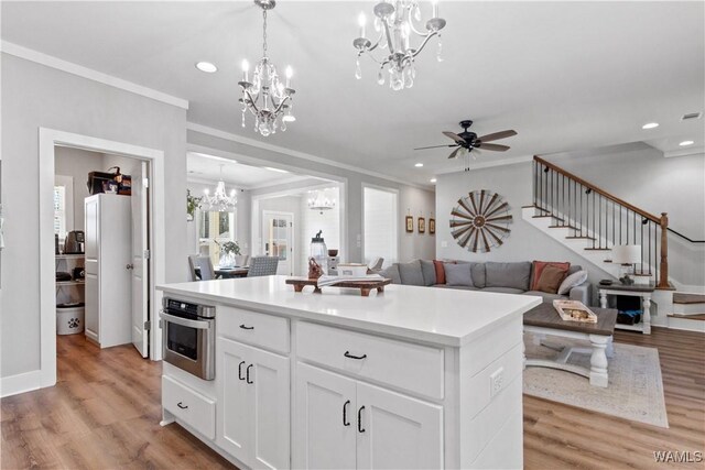 kitchen featuring hanging light fixtures, light wood-style flooring, ornamental molding, and oven