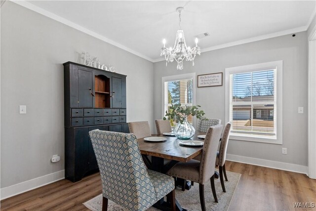 dining area with baseboards, visible vents, ornamental molding, and wood finished floors