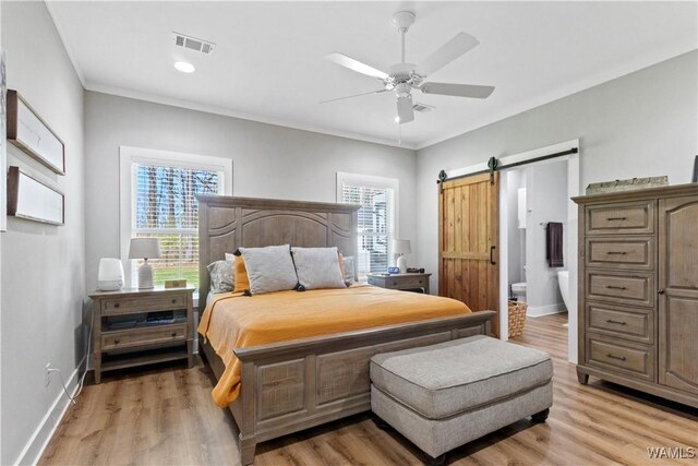 bedroom with a barn door, multiple windows, visible vents, and baseboards