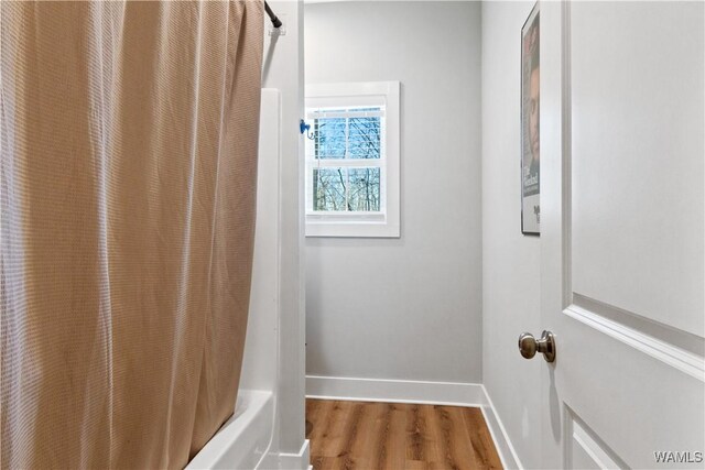 full bath with shower / bathtub combination with curtain, wood finished floors, and baseboards