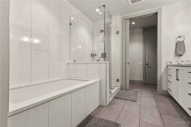 bathroom featuring a stall shower, tile patterned flooring, tiled tub, and vanity