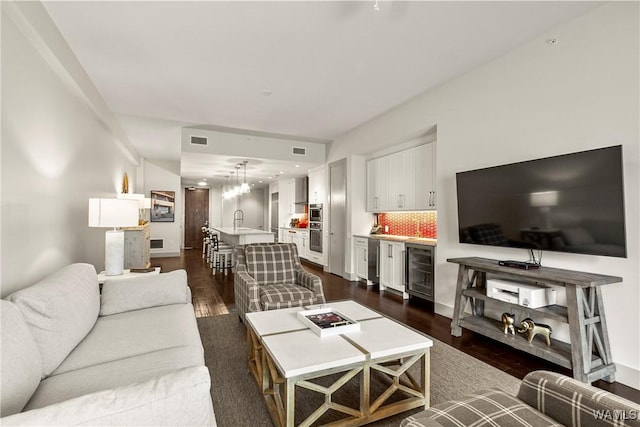 living room featuring wine cooler, visible vents, dark wood finished floors, and indoor bar