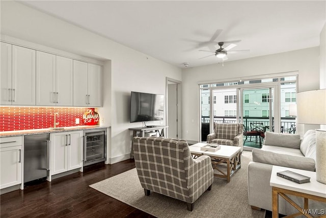 living area featuring ceiling fan, beverage cooler, dark wood-type flooring, bar area, and baseboards