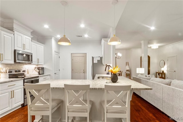 13862 Willow View Ln, Northport, AL 35475 - kitchen with stainless steel appliances, dark wood finished floors, a breakfast bar, white cabinets, and crown molding