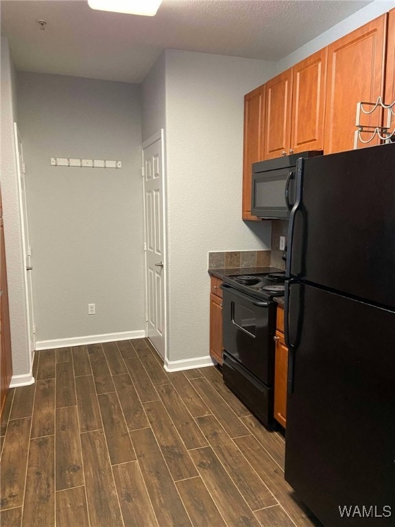 kitchen featuring a textured ceiling, black appliances, and dark hardwood / wood-style floors