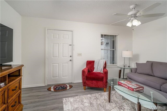 living room featuring wood-type flooring, a textured ceiling, and ceiling fan