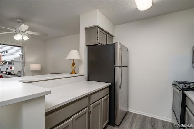 kitchen featuring stainless steel refrigerator, ceiling fan, gray cabinetry, black electric range, and dark hardwood / wood-style flooring