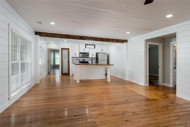 11376 Kings Loop Rd, Tuscaloosa, AL 35405 - kitchen with stainless steel appliances, light wood-type flooring, white cabinets, open floor plan, and wood walls