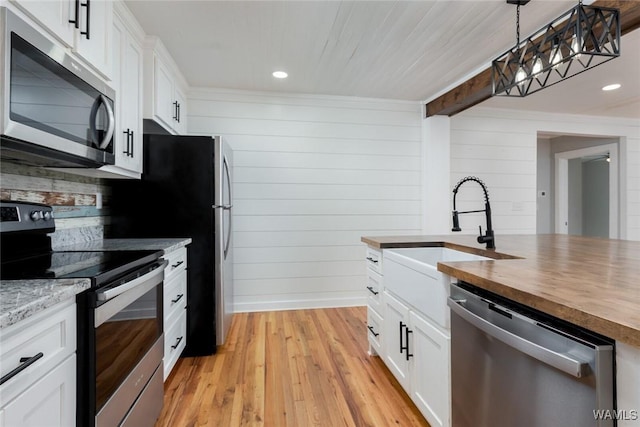 11376 Kings Loop Rd, Tuscaloosa, AL 35405 - kitchen with stainless steel appliances, butcher block countertops, light wood finished floors, white cabinets, and hanging light fixtures