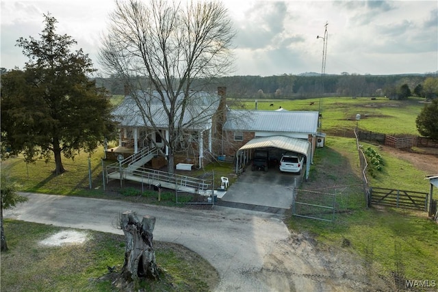 view of front facade with a detached carport, a gate, fence, a rural view, and driveway