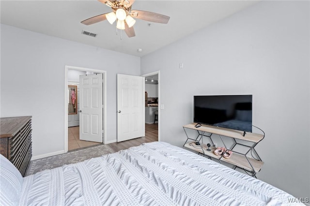 bedroom with ensuite bath, ceiling fan, baseboards, and visible vents