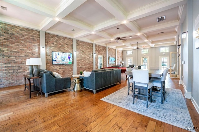 dining space with visible vents, coffered ceiling, beamed ceiling, brick wall, and ceiling fan