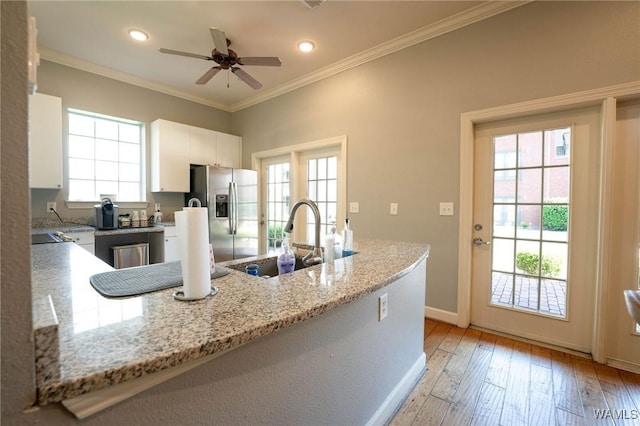 kitchen with white cabinets, a sink, crown molding, stainless steel fridge, and ceiling fan