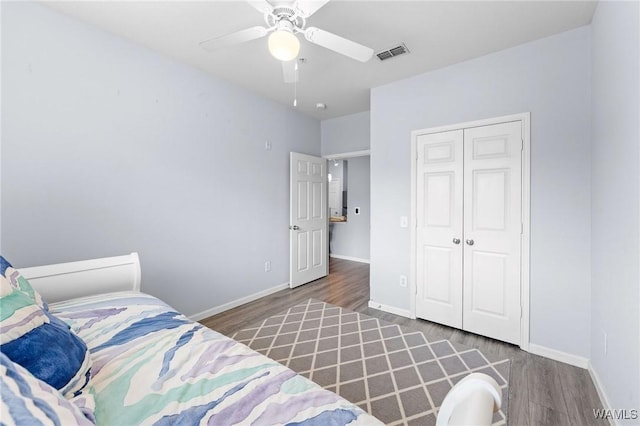 bedroom featuring baseboards, visible vents, a ceiling fan, wood finished floors, and a closet