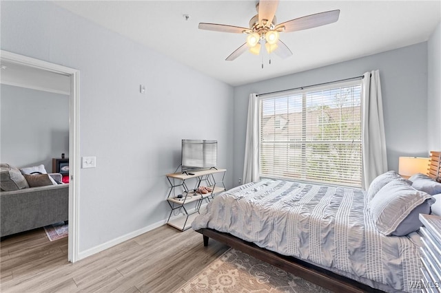 bedroom with light wood-style flooring, a ceiling fan, and baseboards