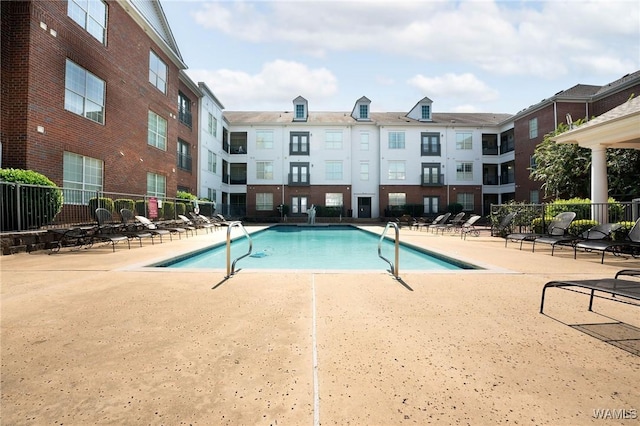 community pool with fence and a patio
