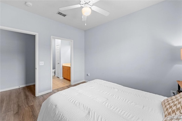 bedroom with visible vents, a ceiling fan, light wood-type flooring, baseboards, and ensuite bathroom