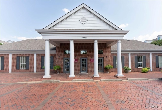 neoclassical / greek revival house with brick siding and a shingled roof