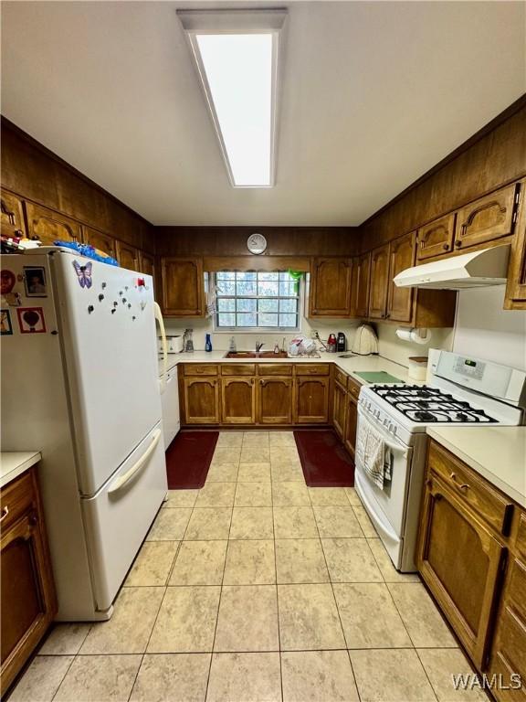 kitchen featuring crown molding, sink, light tile patterned floors, and white appliances