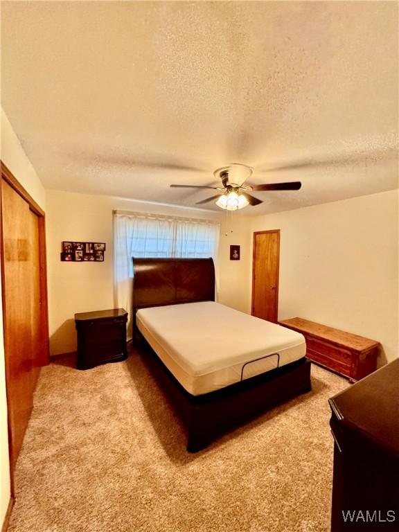 carpeted bedroom featuring a textured ceiling, a closet, and ceiling fan