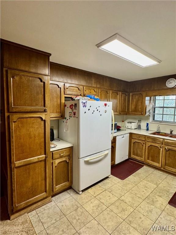 kitchen with white appliances, sink, and light tile patterned floors