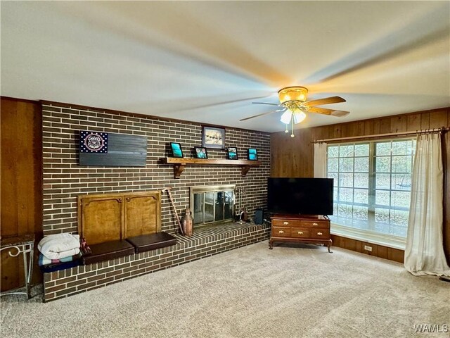 interior space with wooden walls, a fireplace, carpet, and ceiling fan