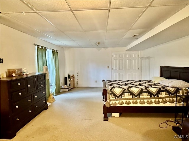 carpeted bedroom featuring a drop ceiling and a closet