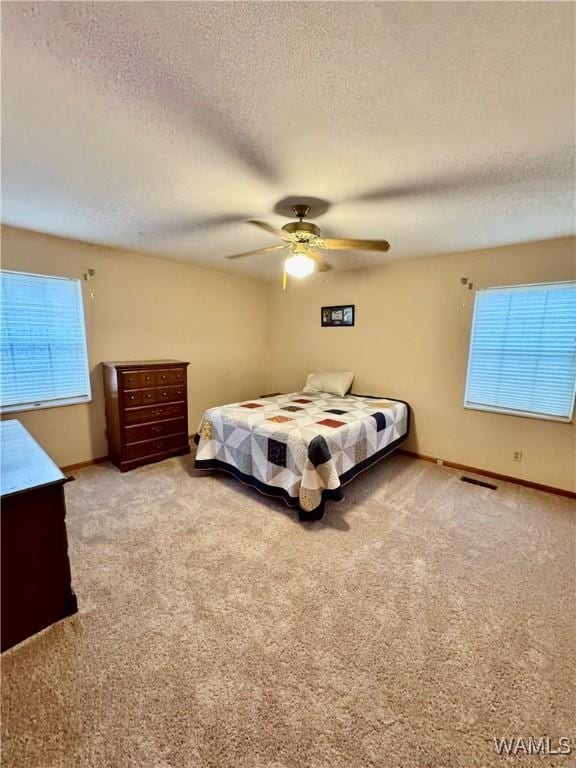 carpeted bedroom with ceiling fan and a textured ceiling