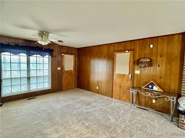 spare room with carpet flooring, ceiling fan, and wood walls