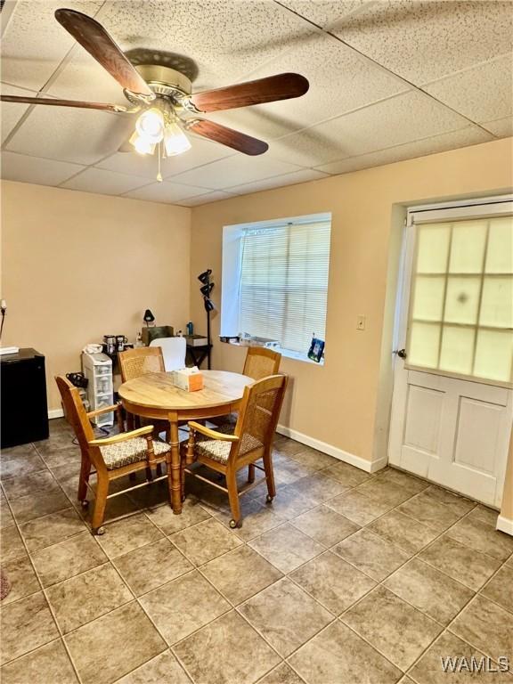 dining area with tile patterned floors, ceiling fan, and a drop ceiling