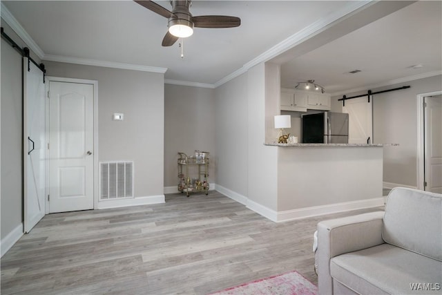 sitting room with crown molding, ceiling fan, a barn door, and light hardwood / wood-style floors