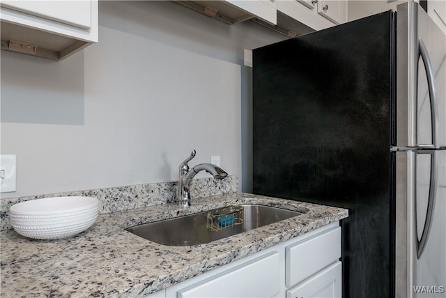 kitchen with white cabinetry, sink, and stainless steel fridge