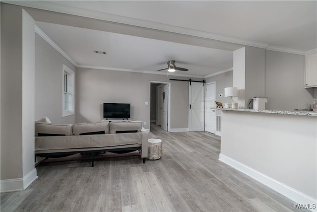 living room with crown molding, ceiling fan, a barn door, and light hardwood / wood-style flooring