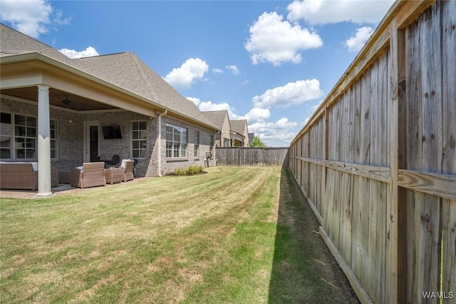 view of yard with a fenced backyard, ceiling fan, and an outdoor living space