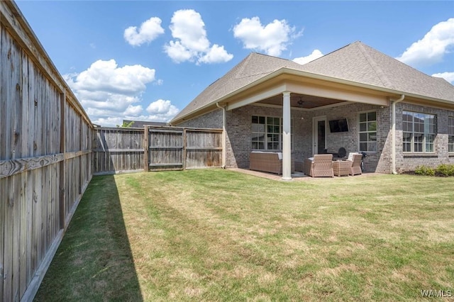 back of property with brick siding, a ceiling fan, a fenced backyard, and an outdoor hangout area