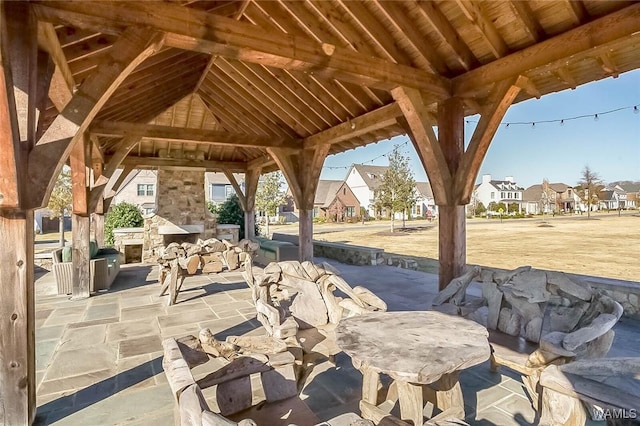 view of patio / terrace featuring an outdoor stone fireplace, a gazebo, and a residential view