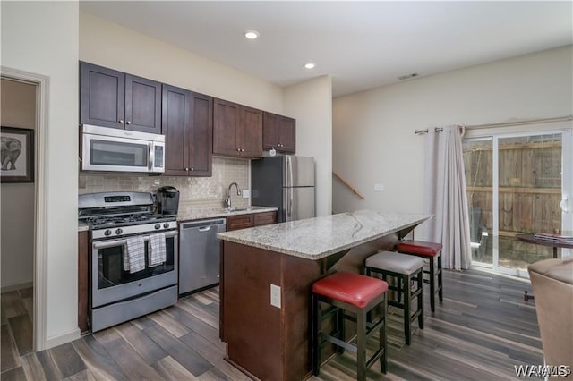 702 Gene Stallings Ave, Tuscaloosa, AL 35401 - kitchen with backsplash, a kitchen island, a breakfast bar, stainless steel appliances, and dark wood-style flooring