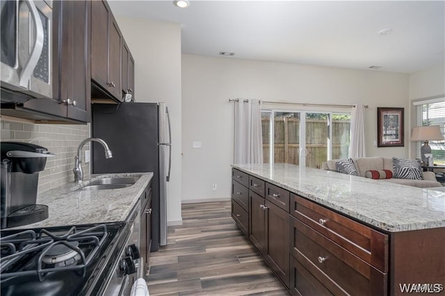 702 Gene Stallings Ave, Tuscaloosa, AL 35401 - kitchen featuring a sink, stainless steel microwave, tasteful backsplash, wood finished floors, and light stone countertops