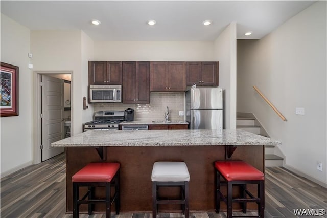 702 Gene Stallings Ave, Tuscaloosa, AL 35401 - kitchen with dark brown cabinetry, a kitchen breakfast bar, backsplash, and appliances with stainless steel finishes