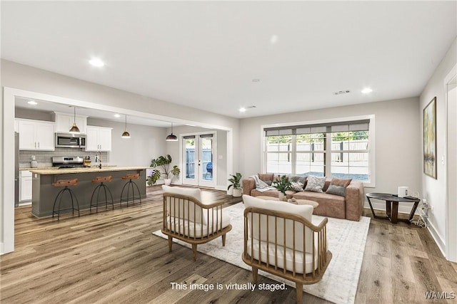 living room with french doors and light wood-type flooring