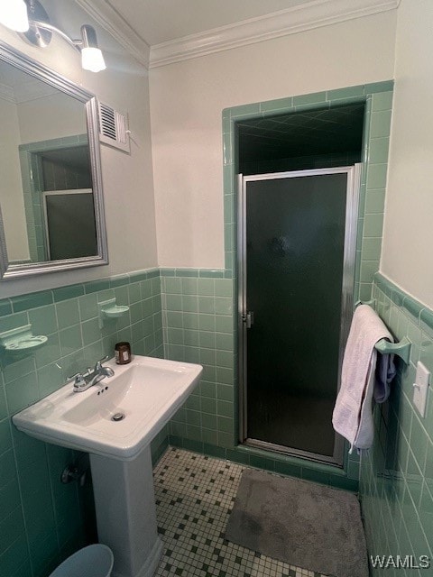 bathroom with tile patterned flooring, tile walls, crown molding, and walk in shower