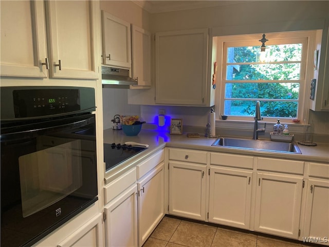 kitchen featuring white cabinetry, sink, decorative backsplash, light tile patterned flooring, and black appliances