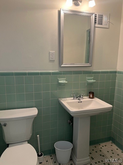 bathroom featuring tile patterned floors, tile walls, and toilet