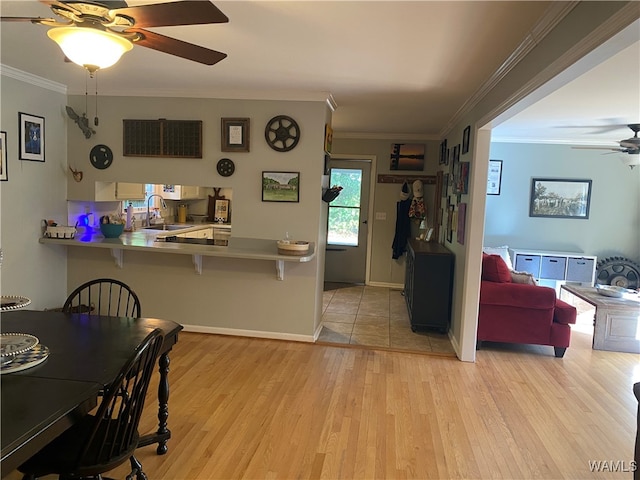 kitchen featuring ceiling fan, sink, kitchen peninsula, light hardwood / wood-style floors, and ornamental molding